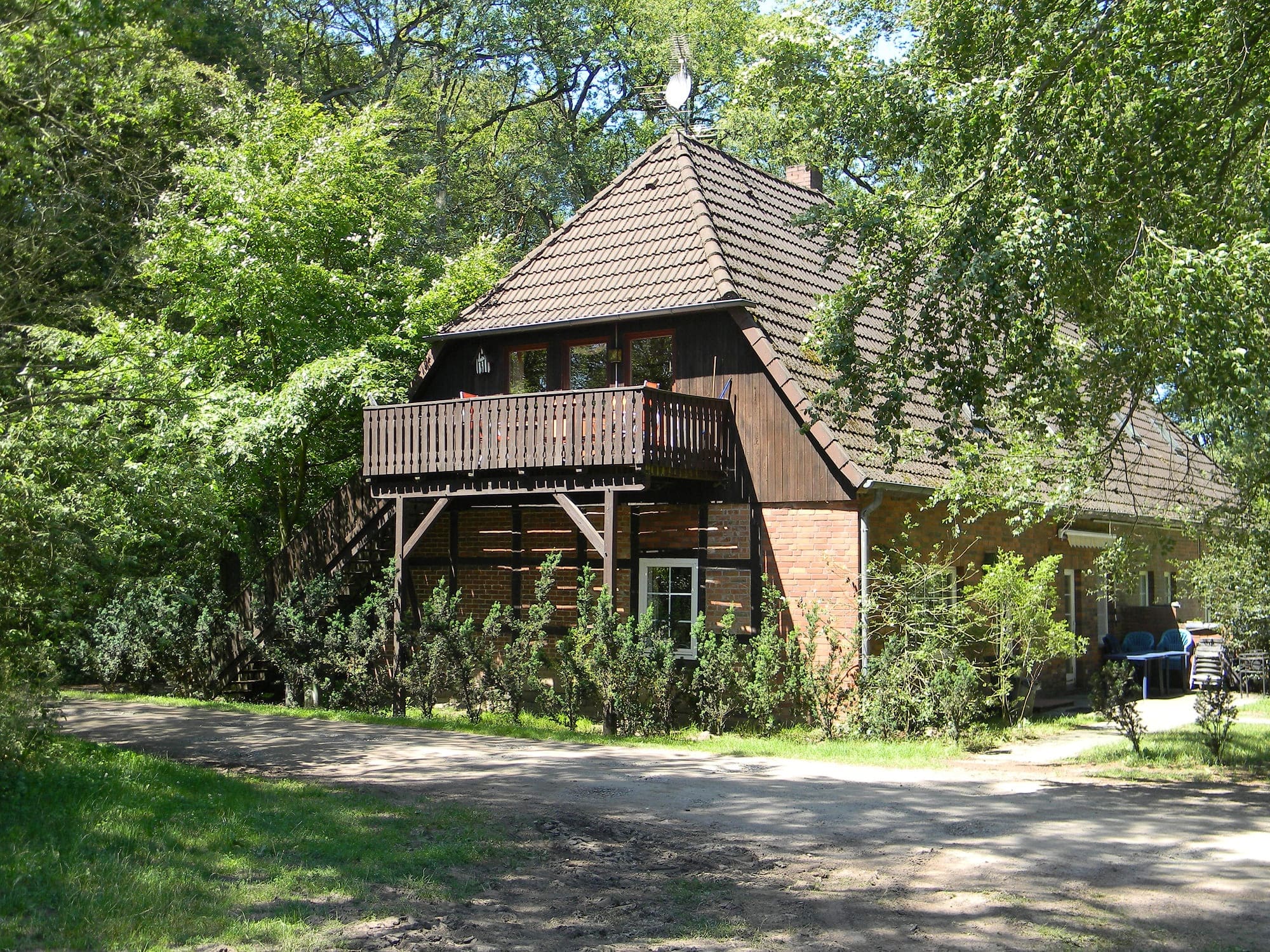Rustikales Backsteinhaus mit Holz-Balkon und Fachwerkelementen im Grünen